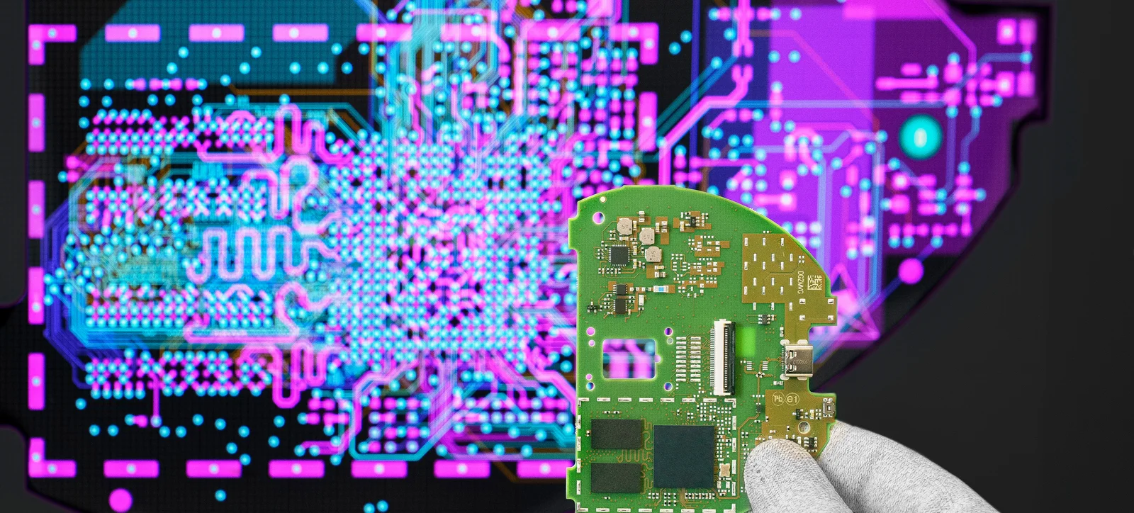 Cicor engineer holding a PCB in front of a screen displaying the PCB design